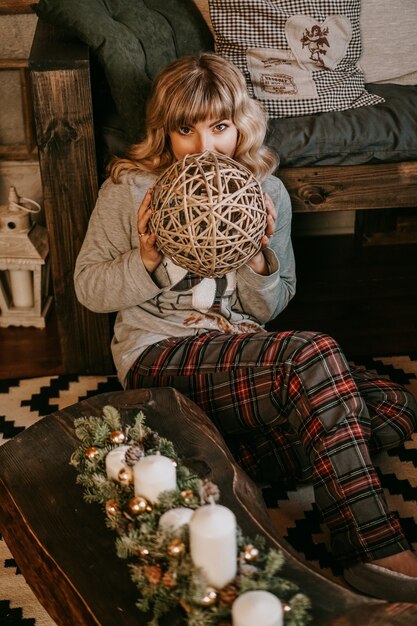 Jonge mooie vrouw in pyjama's in de buurt van decoratieve open haard. Kerstsfeer, Nieuwjaar