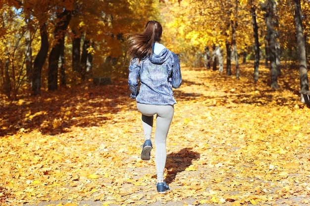 Jonge mooie vrouw joggen in herfst park