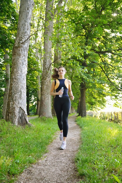 Jonge mooie vrouw joggen op ochtend in het park. Vrouw in sport buitenshuis gezondheidsconcept