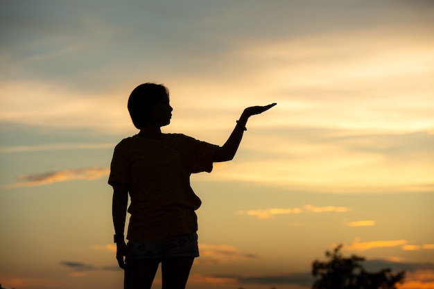 Jonge mooie vrouw kijkt hoopvol naar haar handen bij sunset.concept succes in de hand