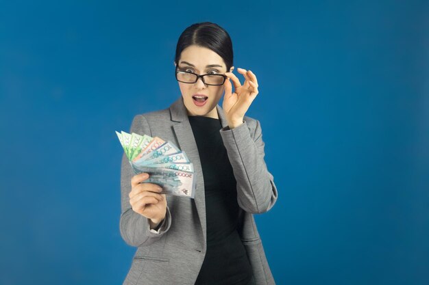 Jonge mooie vrouw kijkt verbaasd naar een pak tenge in haar hand Selectieve focus