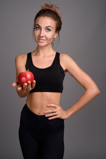 Jonge mooie vrouw klaar voor gym tegen grijze muur