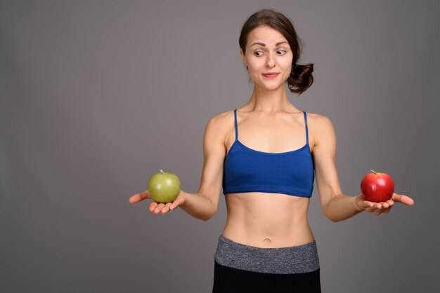 Jonge mooie vrouw klaar voor gym tegen grijze muur