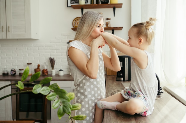 Jonge mooie vrouw knuffelt en kust haar schattige dochtertje. tonen.