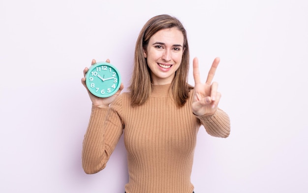 Jonge mooie vrouw lacht en ziet er gelukkig uit, gebarend overwinning of vrede. wekker