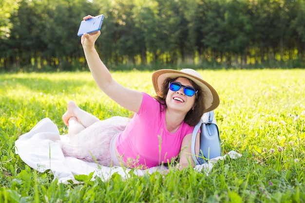 Jonge mooie vrouw maakt selfie foto op smartphone op een picknick in de zomer.