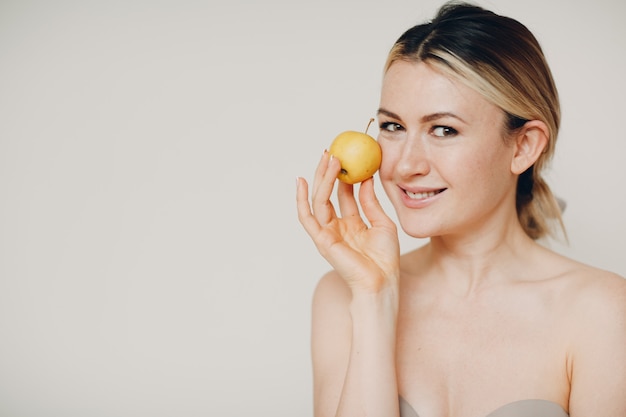 Jonge mooie vrouw met appel in de buurt van gezicht, jeugd en huid natuurlijke verzorging cosmetica concept