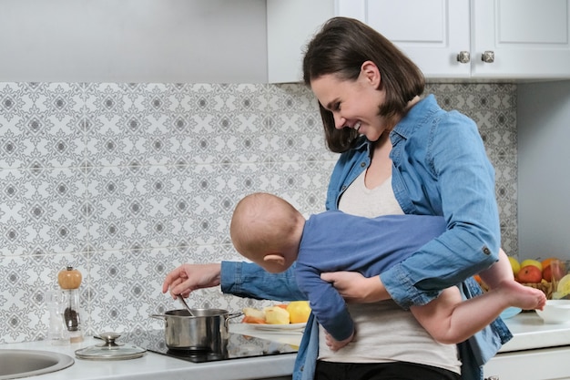 Jonge mooie vrouw met baby in haar armen in de keuken