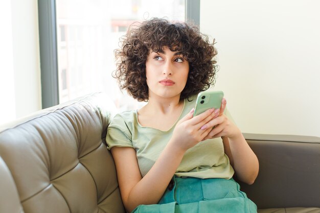 Jonge mooie vrouw met behulp van haar slimme telefoon in het nieuwe huis