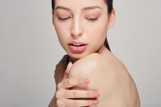 Jonge mooie vrouw met blauwe ogen en volle lippen houdt een hand op zijn schouder.