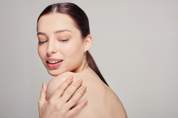 Jonge mooie vrouw met blauwe ogen en volle lippen houdt een hand op zijn schouder.