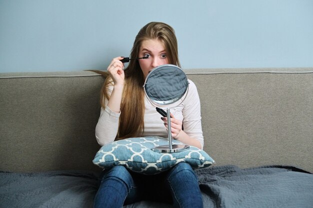 Jonge mooie vrouw met de decoratieve schoonheidsmiddelen die van de samenstellingsspiegel make-up doen