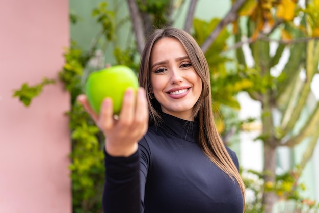 Jonge mooie vrouw met een appel in de open lucht