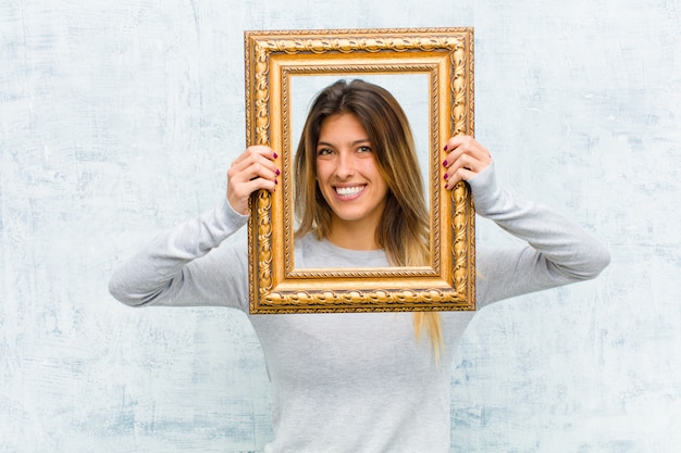 Jonge mooie vrouw met een barok frame tegen grungemuur