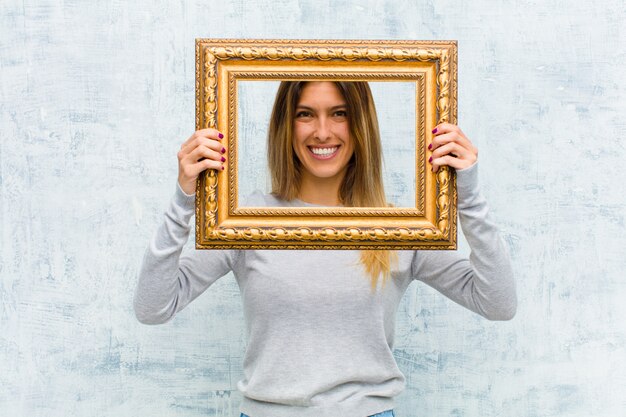 Jonge mooie vrouw met een barok frame tegen grungemuur