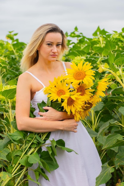 Jonge mooie vrouw met een boeket zonnebloemen in een veld met zonnebloemen