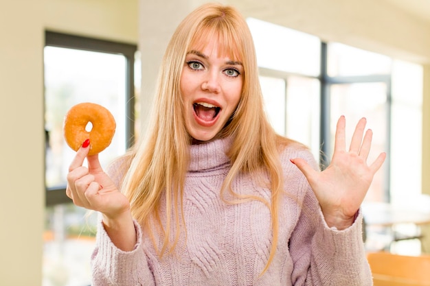 Foto jonge mooie vrouw met een donut ongezond dieet concept thuis interieur