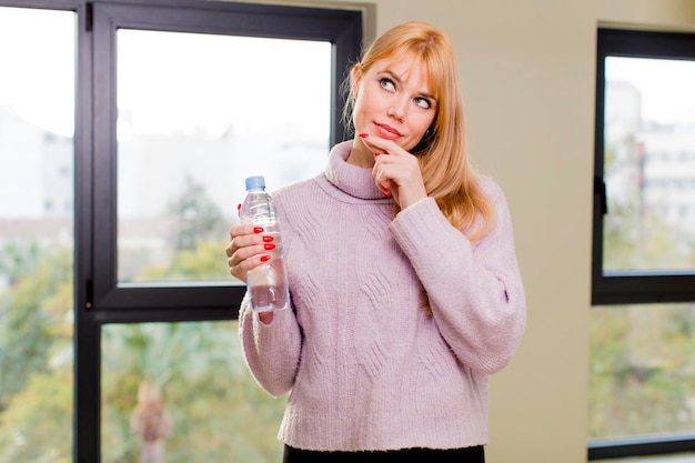 Jonge mooie vrouw met een fles water thuis interieur