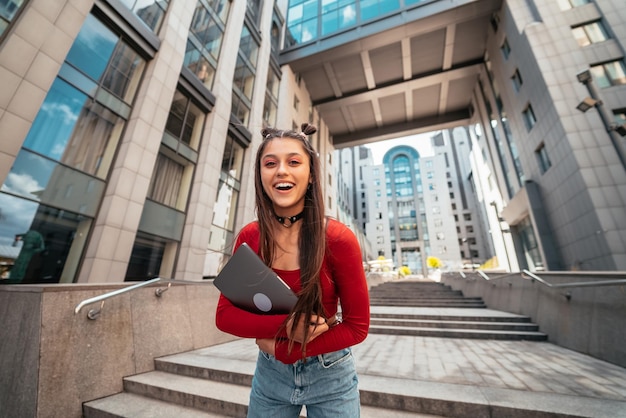 Jonge mooie vrouw met een laptop op straat