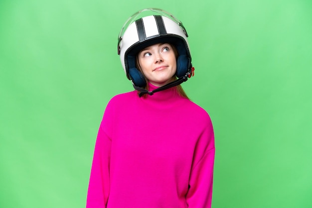 Jonge mooie vrouw met een motorhelm over geïsoleerde chroma key achtergrond en omhoog kijkend