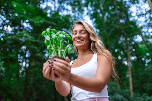 Jonge mooie vrouw met een plant die uit de grond groeit