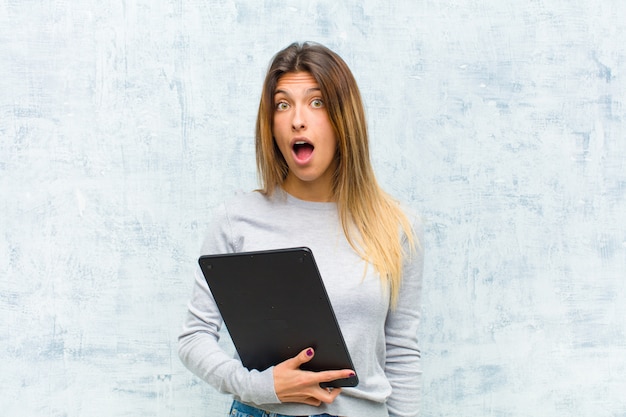 Jonge mooie vrouw met een tablet tegen grungemuur