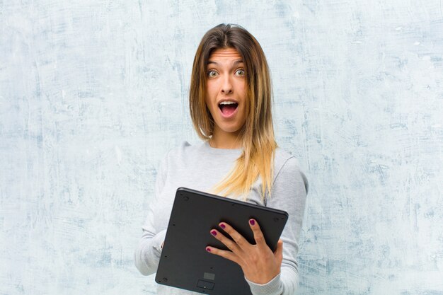 Jonge mooie vrouw met een tablet tegen grungemuur