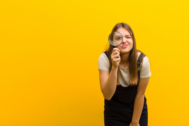 Jonge mooie vrouw met een vergrootglassinaasappel