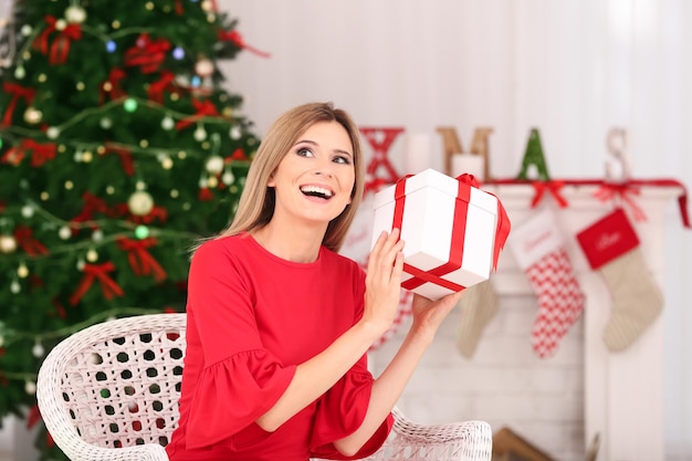 Jonge mooie vrouw met geschenkdoos in kamer ingericht voor Kerstmis