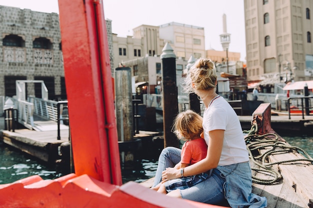 Jonge mooie vrouw met haar zoontje zittend aan boord en overweegt het zeegezicht