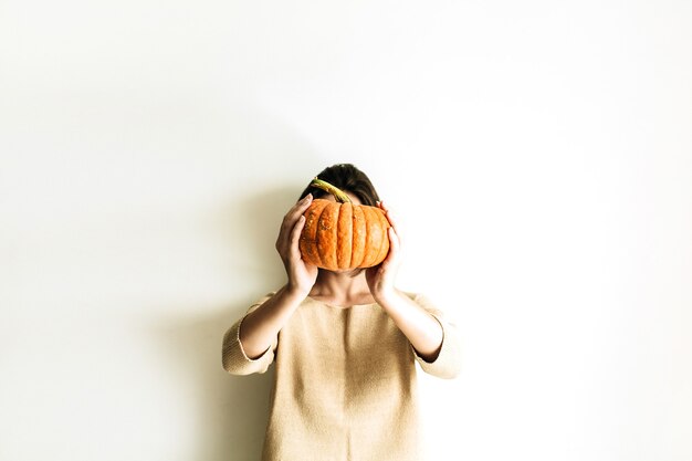 Jonge mooie vrouw met halloween-pompoen op wit oppervlak