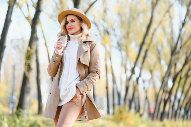 Jonge mooie vrouw met kopje koffie in het herfstpark