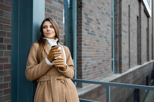 Jonge mooie vrouw met kopje koffie op straat