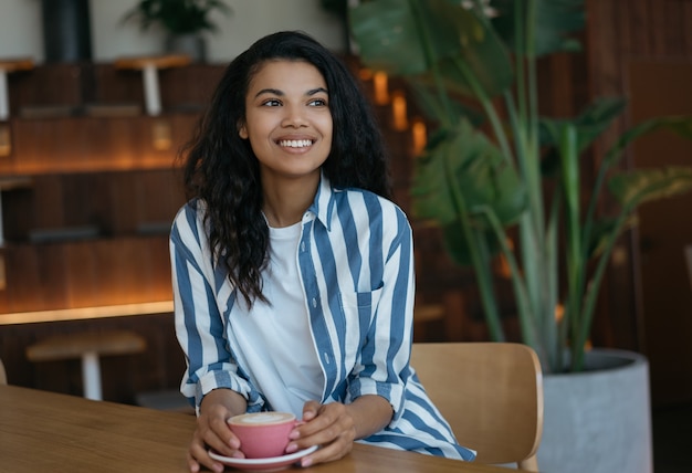 Jonge mooie vrouw met kopje koffie zitten in café