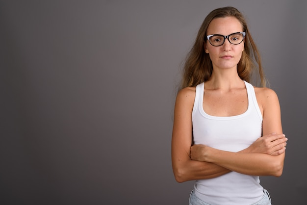 Jonge mooie vrouw met lang blond haar tegen een grijze achtergrond