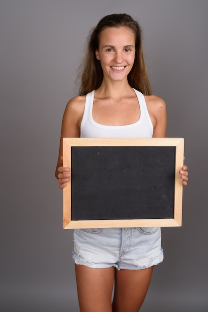 Jonge mooie vrouw met lang blond haar tegen een grijze achtergrond