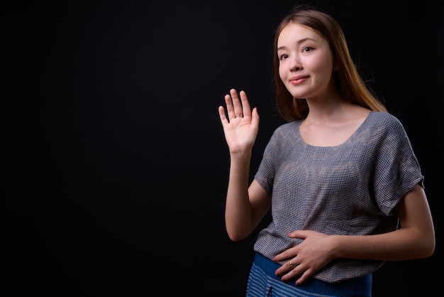 Jonge mooie vrouw met lang bruin haar tegen zwarte muur