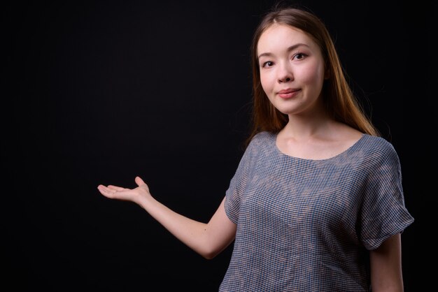 Jonge mooie vrouw met lang bruin haar tegen zwarte muur