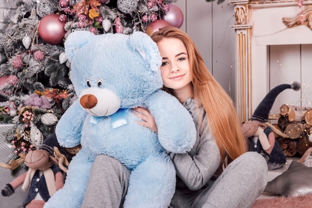 Jonge mooie vrouw met lang golvend haar met een grote blauwe teddybeer