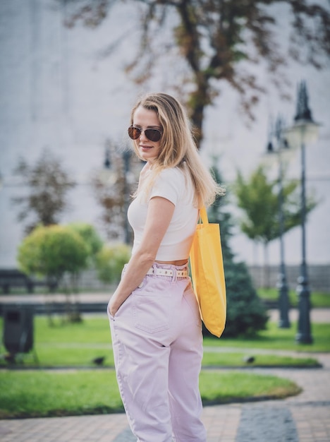 Jonge mooie vrouw met linnen eco tas op de achtergrond van de stad.