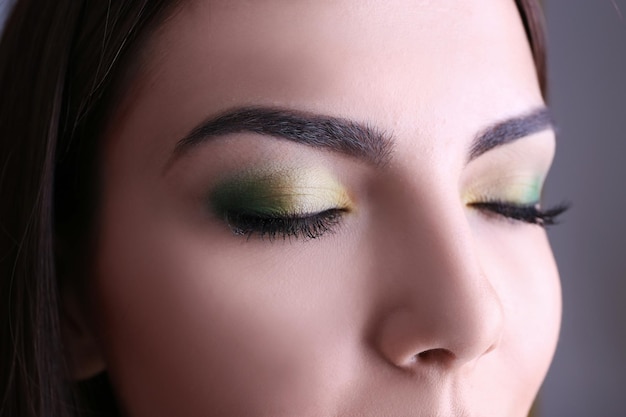 Jonge mooie vrouw met mooie groene make-up close-up