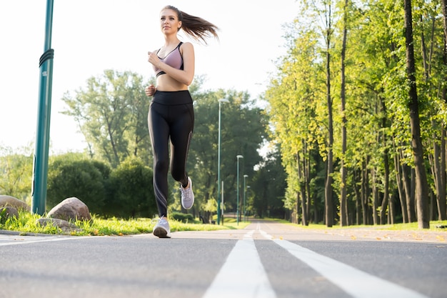 Jonge mooie vrouw met perfect slank lichaam dat buiten loopt. Fitness en hardlopen concept.