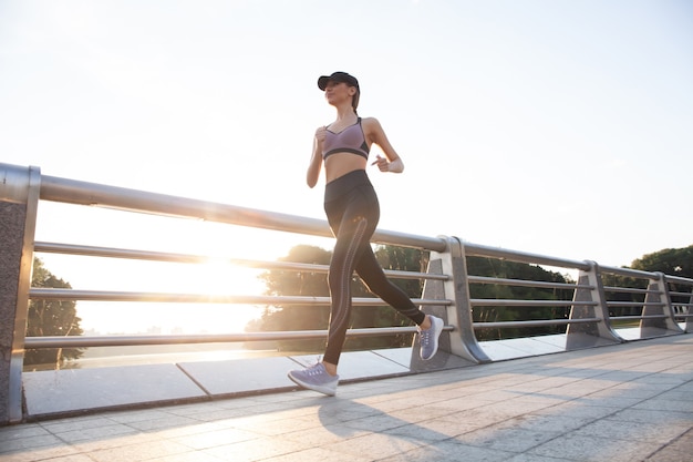 Jonge mooie vrouw met perfect slank lichaam dat buiten loopt. Fitness en hardlopen concept.