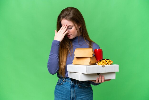 Jonge mooie vrouw met pizza's en hamburgers over geïsoleerde chroma key achtergrond met vermoeide en zieke uitdrukking