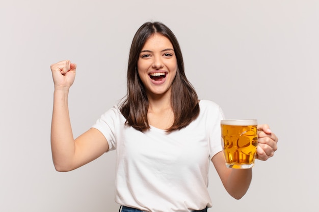 Jonge mooie vrouw met succes een overwinning vieren en een biertje houden