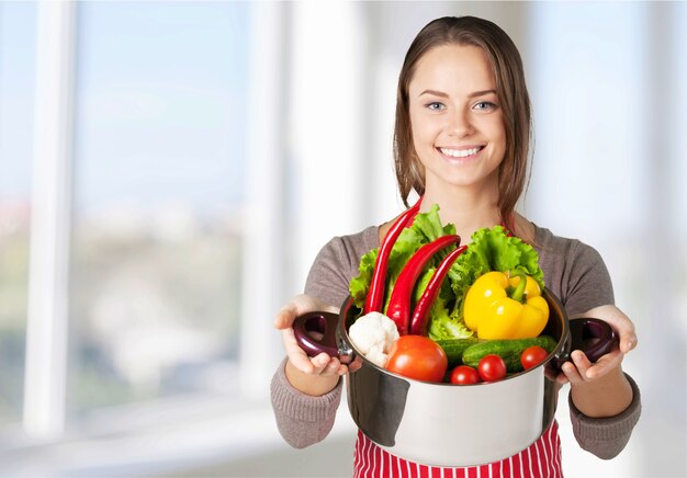 Jonge mooie vrouw met verse groenten koken