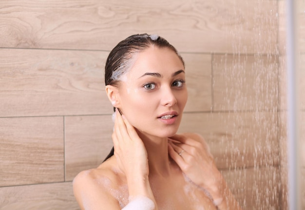 Jonge mooie vrouw onder de douche in de badkamer