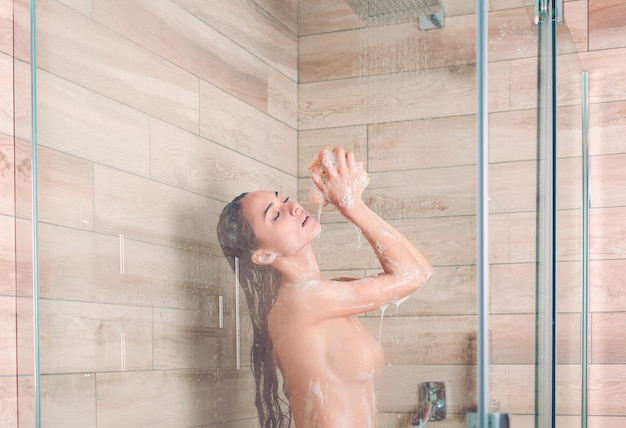 Jonge mooie vrouw onder de douche in de badkamer