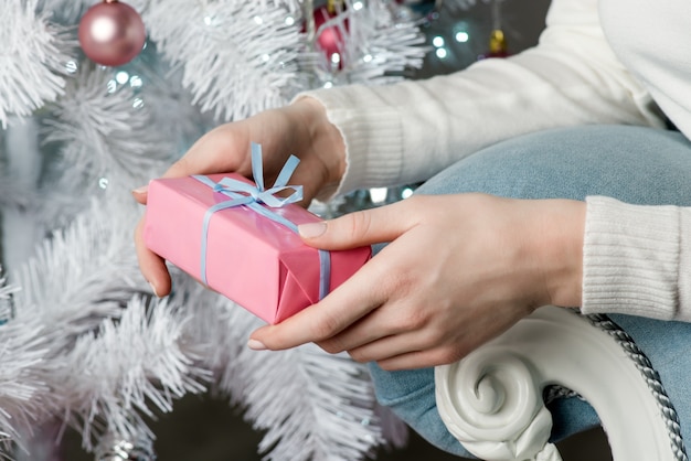 Jonge mooie vrouw onder nieuwjaar boom met kerstcadeau