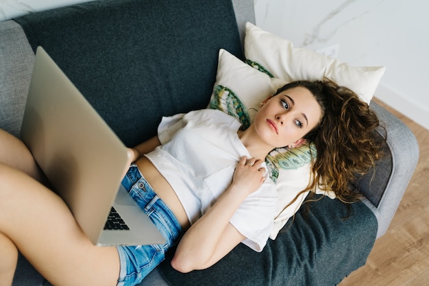 Foto jonge mooie vrouw online winkelen op laptop met creditcard in de hand